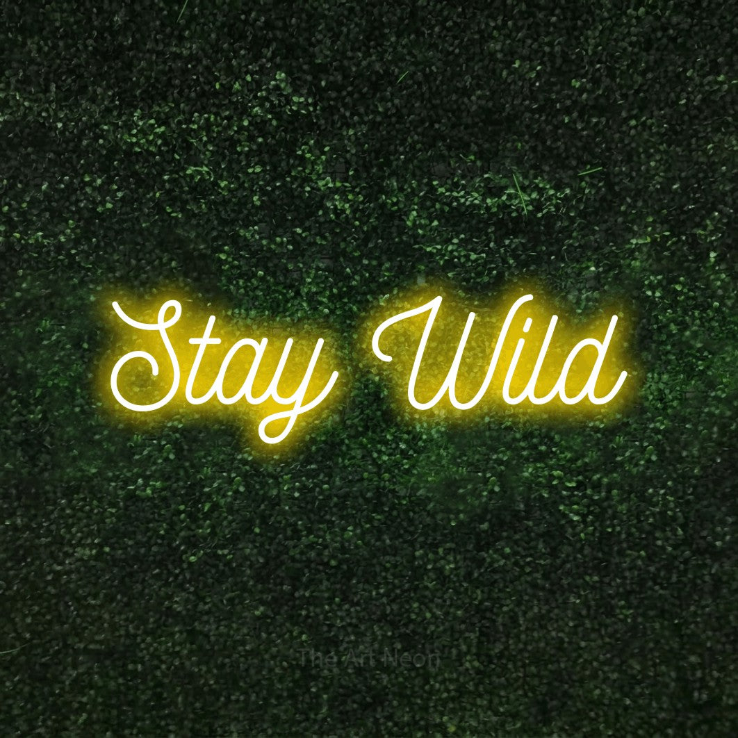 Yellow script-style LED neon sign reading "Stay Wild" against a textured green moss wall for bedroom décor