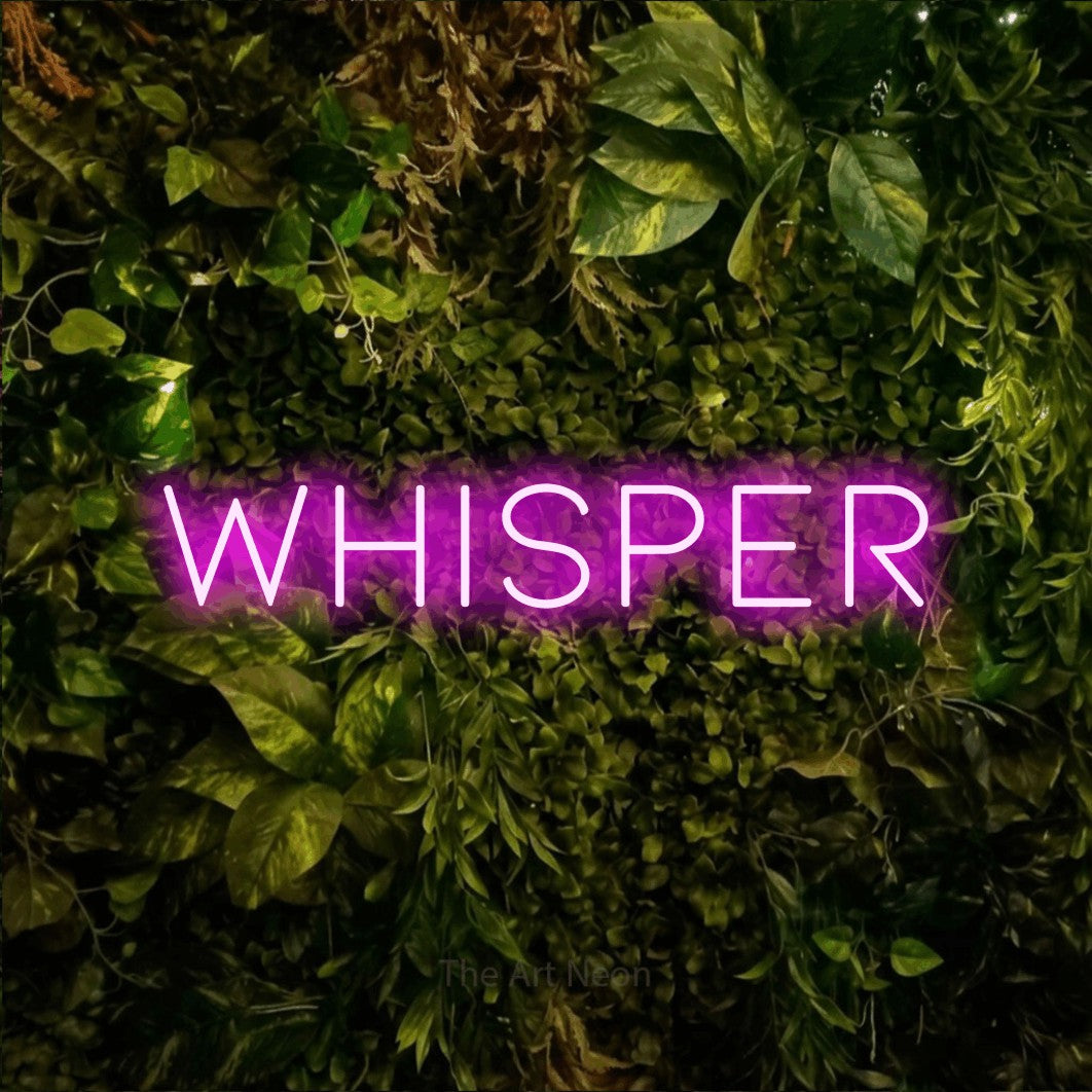 Pink LED neon sign reading "Whisper" against a textured moss and foliage wall for bedroom décor