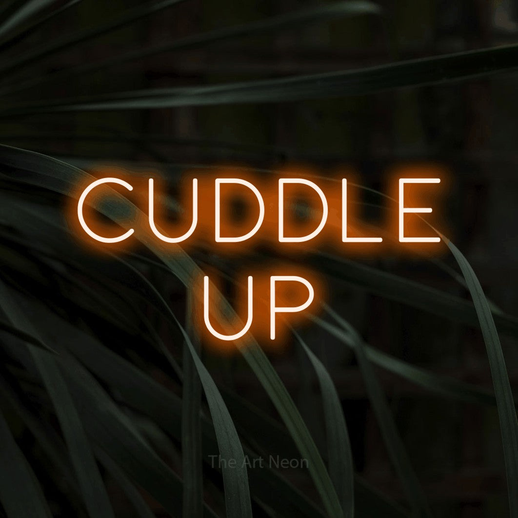 Orange LED neon sign reading "Cuddle Up" against dark tropical leaves for bedroom décor