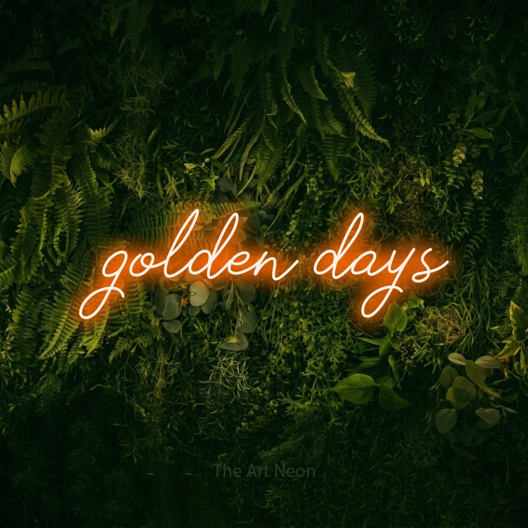Orange script-style LED neon sign reading "Golden Days" against a moss-covered green wall for living room décor