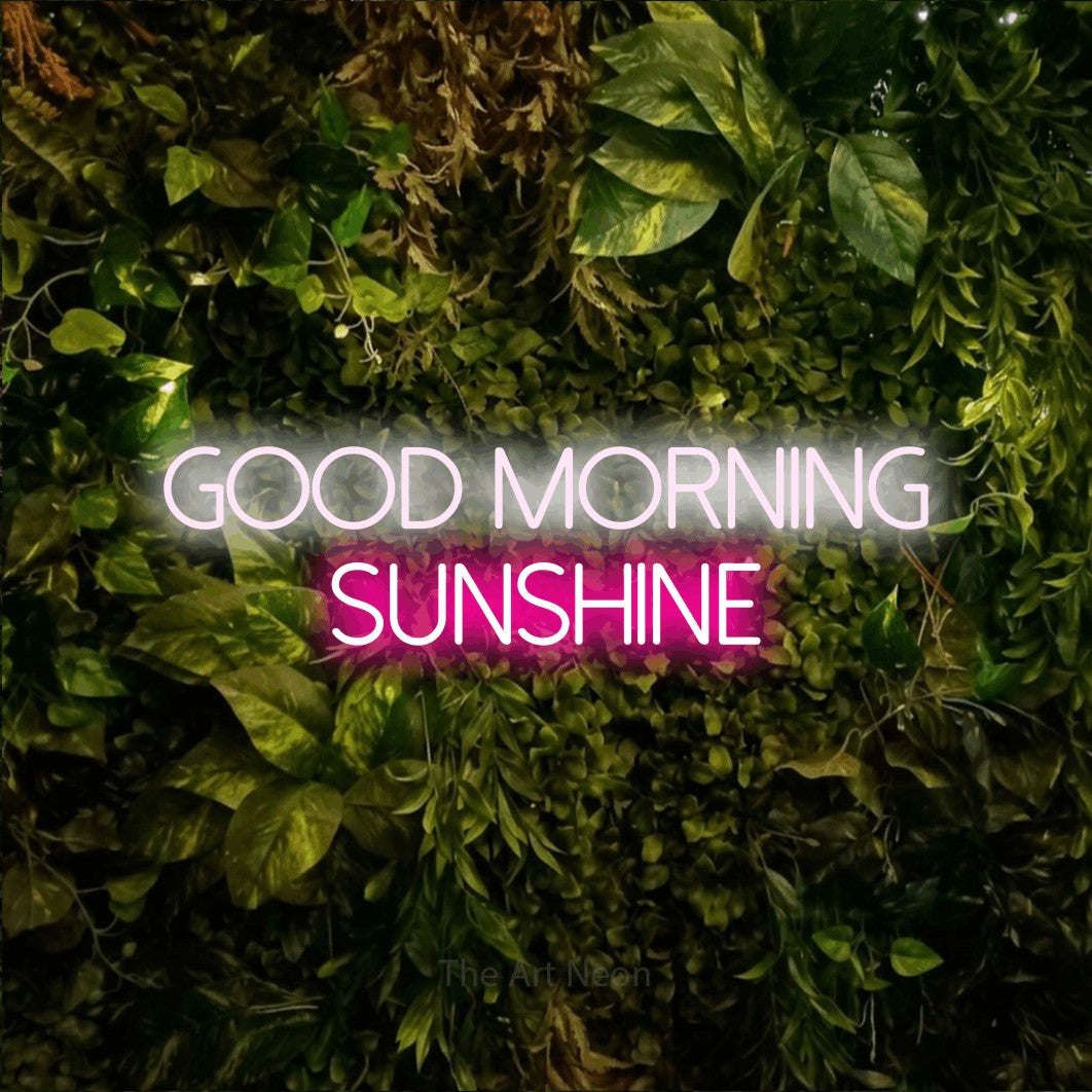 Hot pink and cool white LED neon sign reading "Good Morning Sunshine" against a textured moss and foliage wall