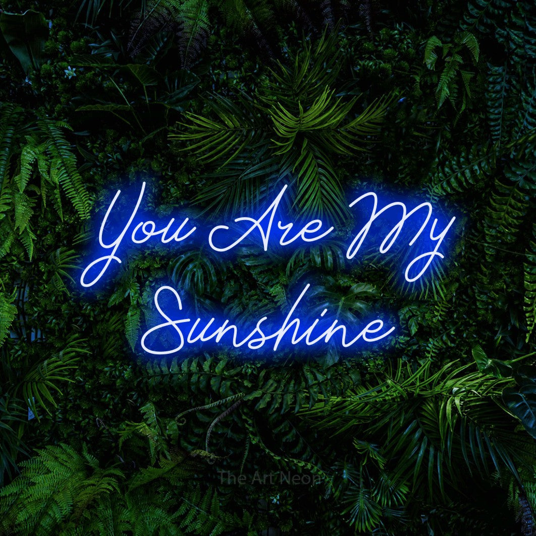 Enseigne néon à DEL à lumière bleue, de style manuscrit, affichant « You Are My Sunshine » sur un mur de feuillage tropical dense, pour décorer une chambre de bébé