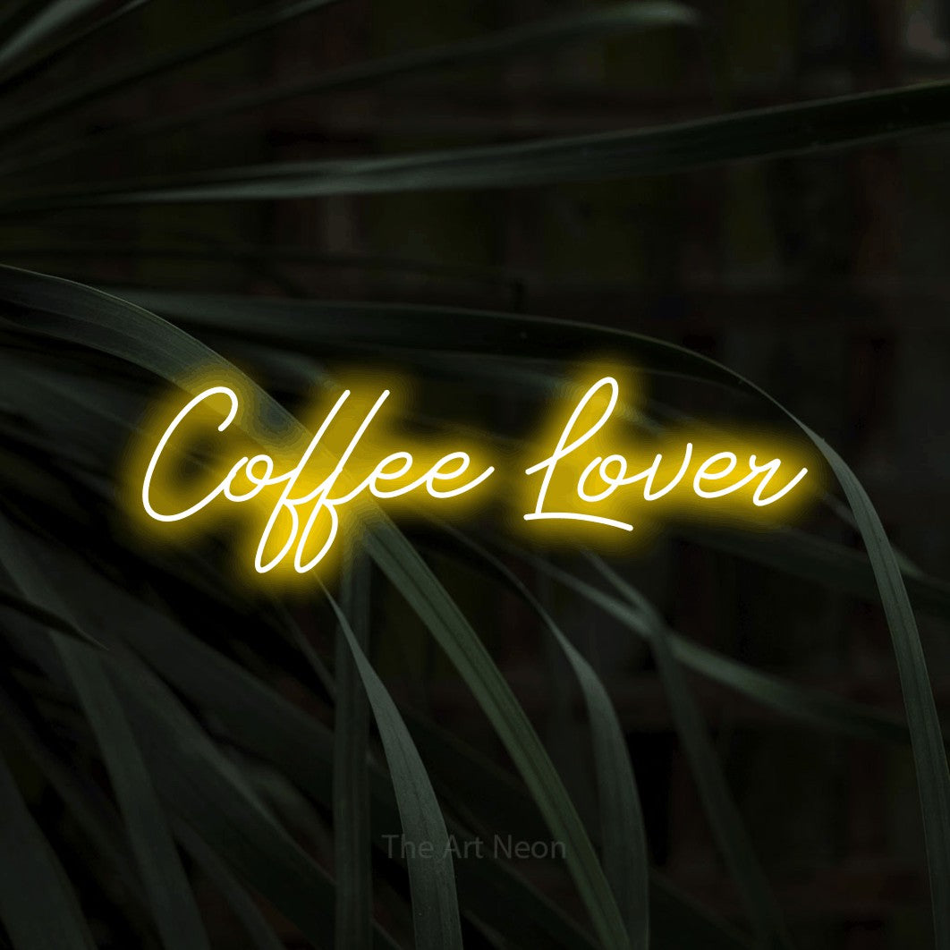 Yellow script-style LED neon sign reading "Coffee Lover" against dark tropical leaves for kitchen décor