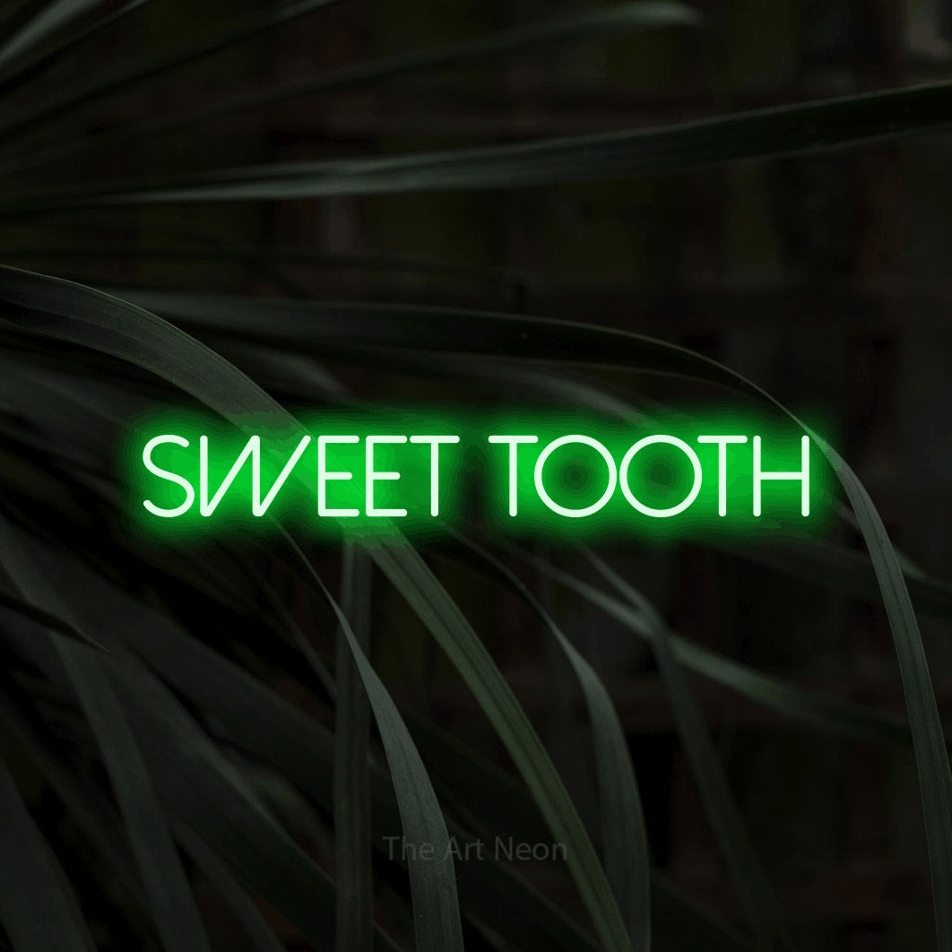 Green LED neon sign reading "Sweet Tooth" against dark tropical leaves for kitchen décor