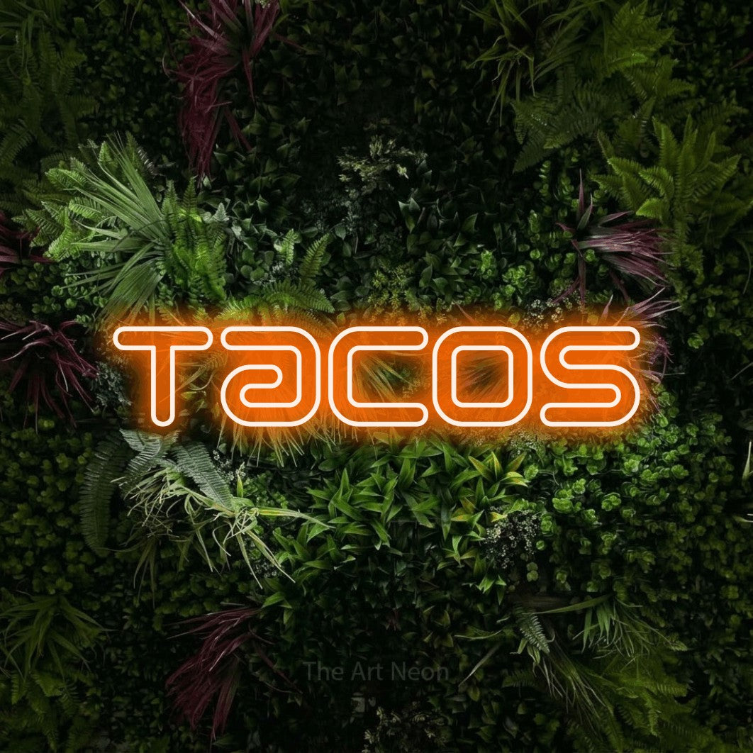 Orange outline-style LED neon sign reading "Tacos" against a lush garden wall with pink flowers for kitchen décor