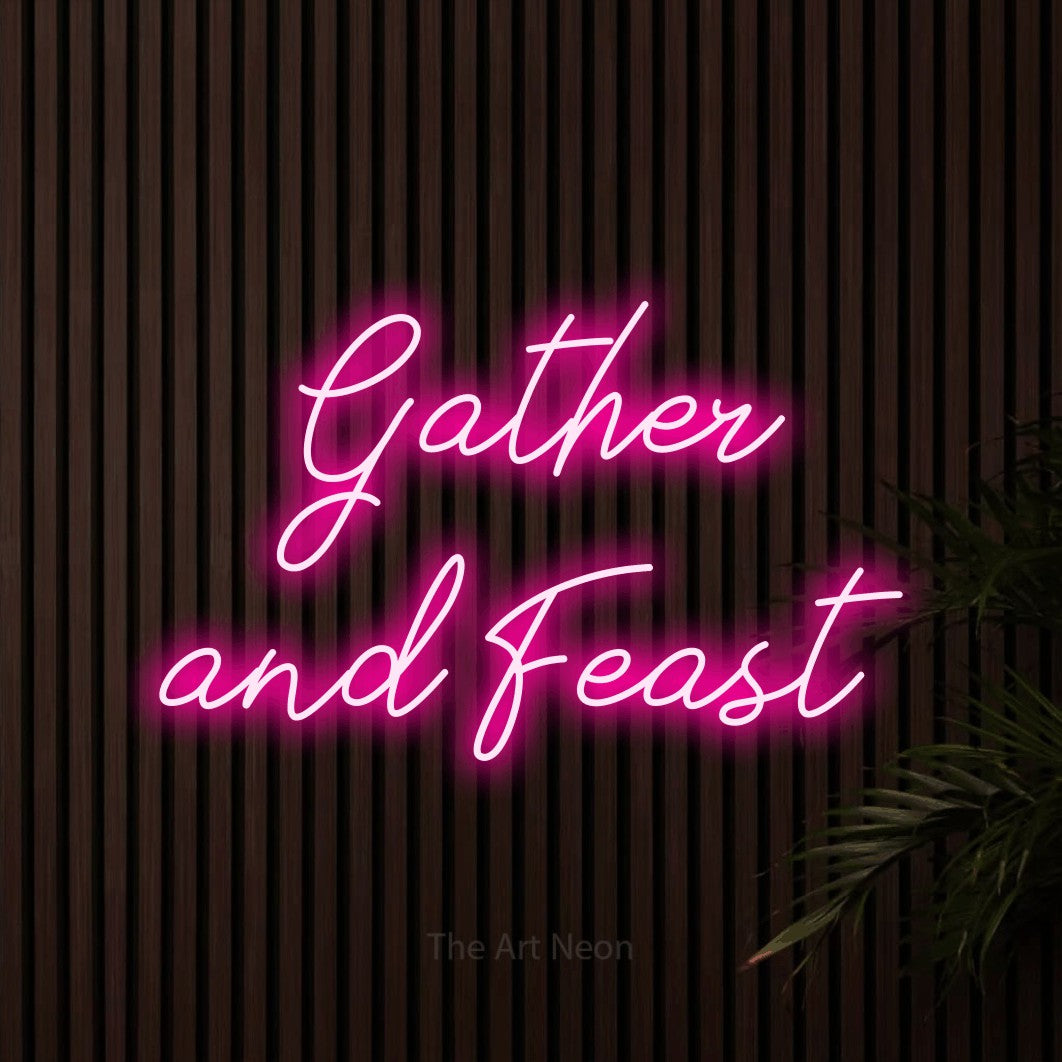 Hot pink script-style LED neon sign reading "Gather and Feast" against dark wooden slats for kitchen décor