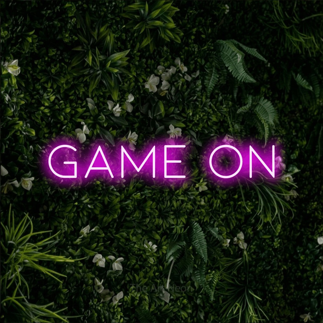 Enseigne néon à DEL à lumière rose, affichant « Game On » sur un mur de feuillage vert, pour décorer une salle de jeu