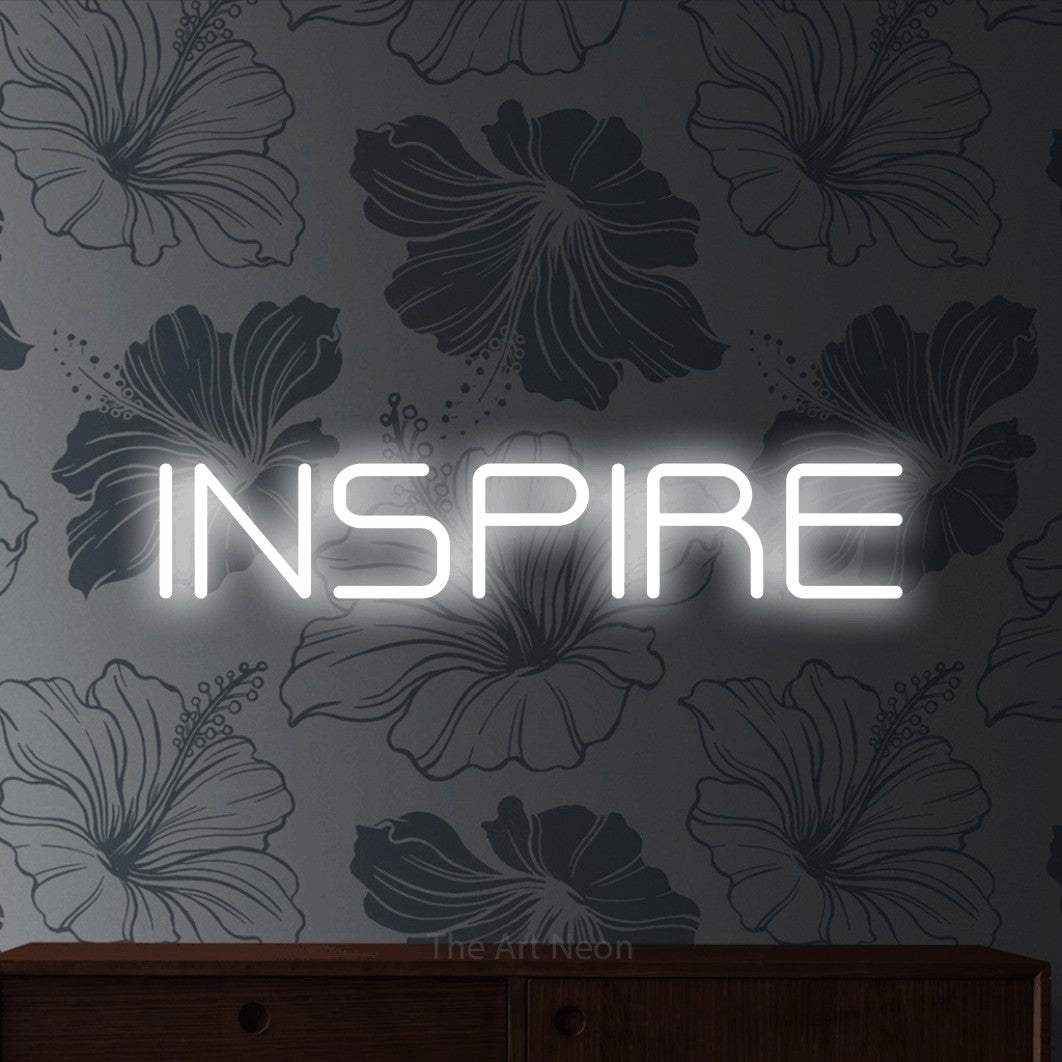Cool white outline-style LED neon sign reading "Inspire" against grey floral wallpaper