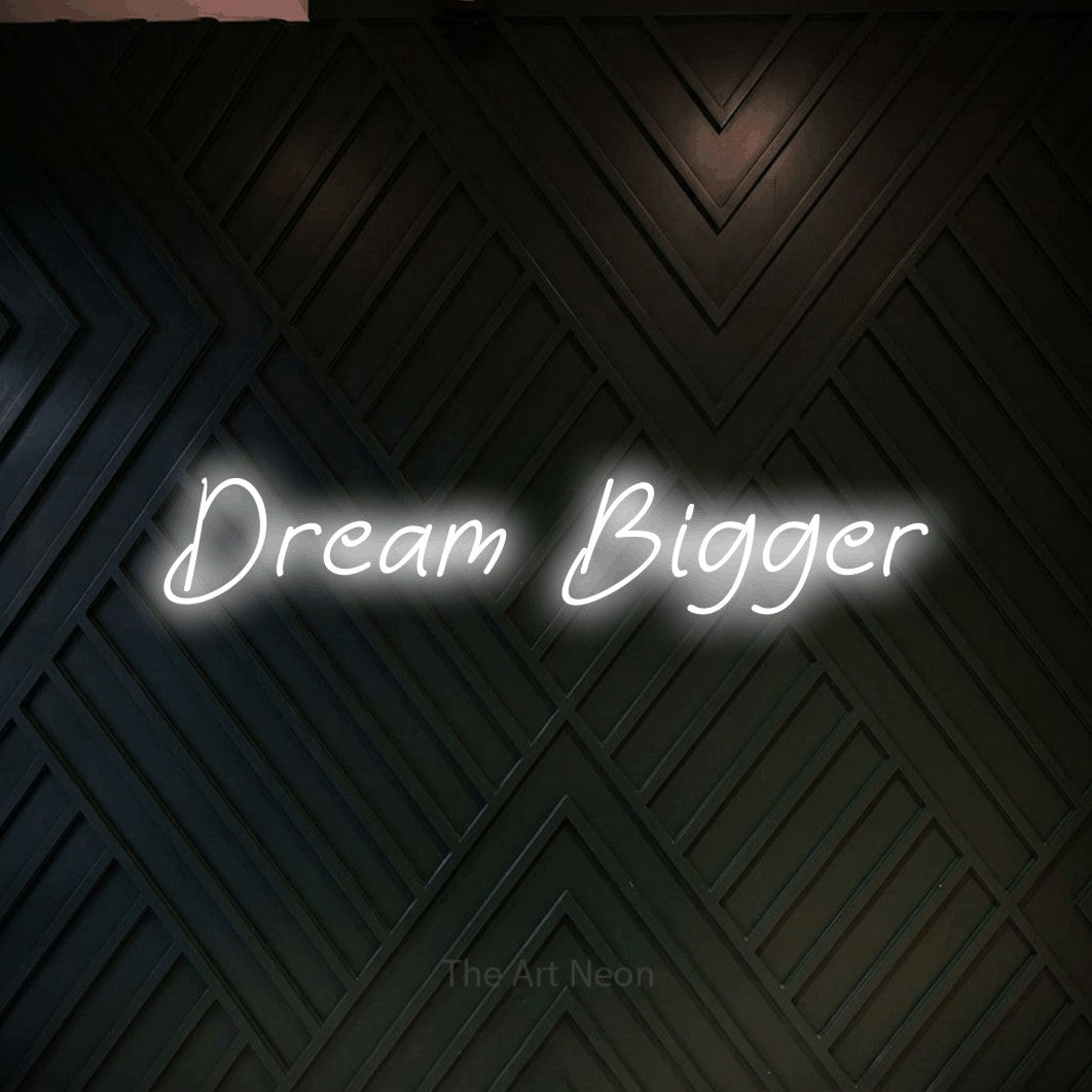 Cool white LED neon sign reading "Dream Bigger" against a dark geometric wood wall