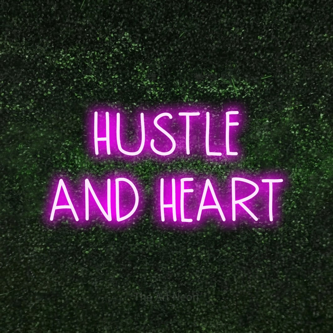 Pink LED neon sign reading "Hustle and Heart" against a textured green moss wall