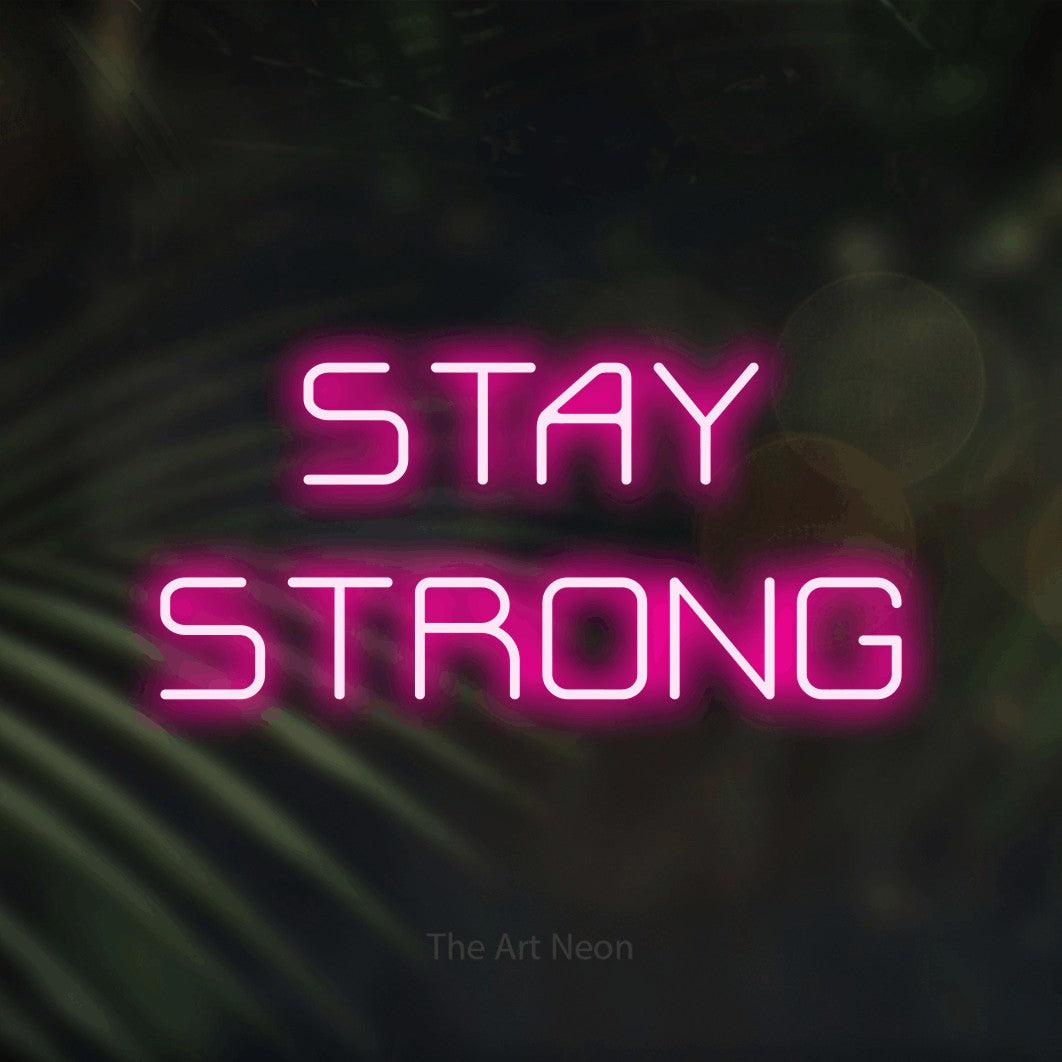 Hot pink LED neon sign reading "Stay Strong" against dark blurred palm leaves