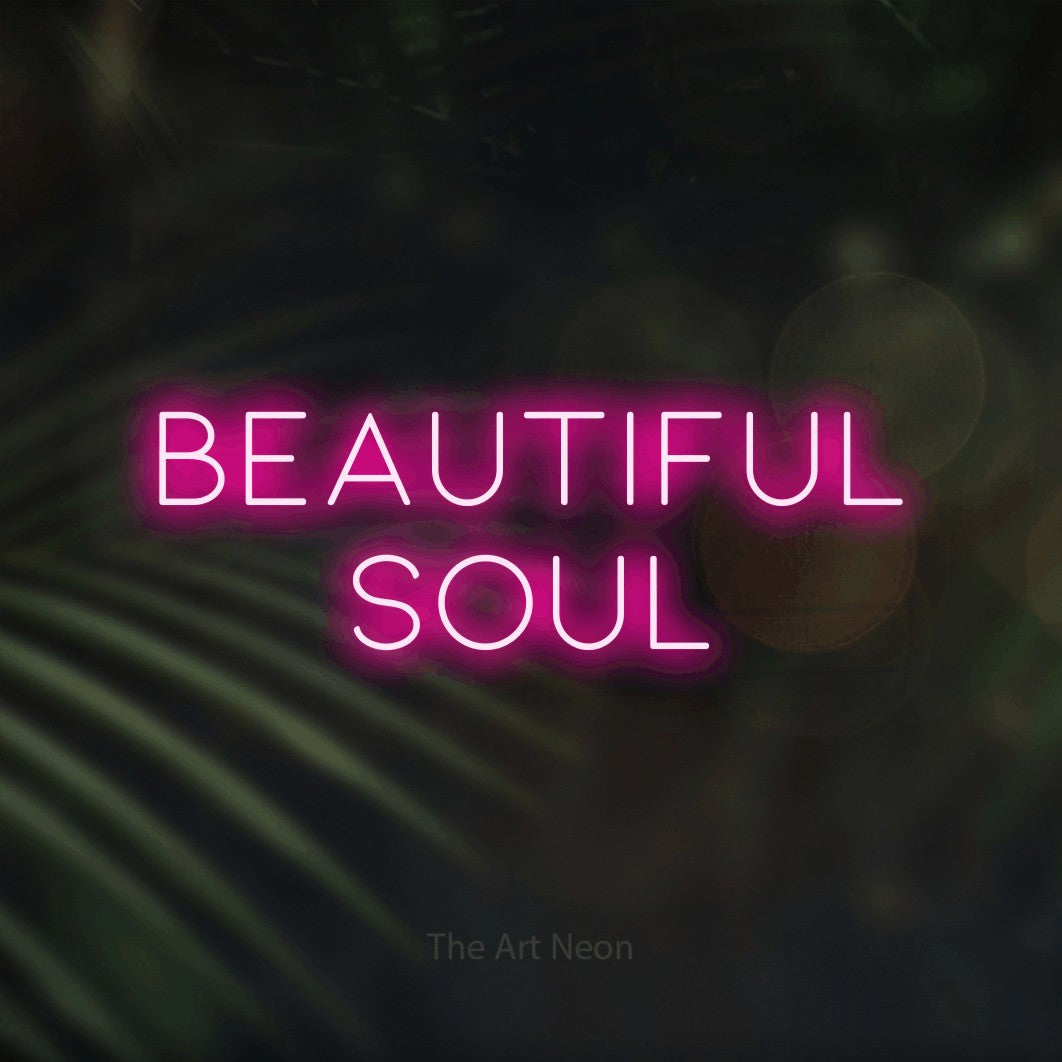 Hot pink LED neon sign reading "Beautiful Soul" against dark blurred palm leaves