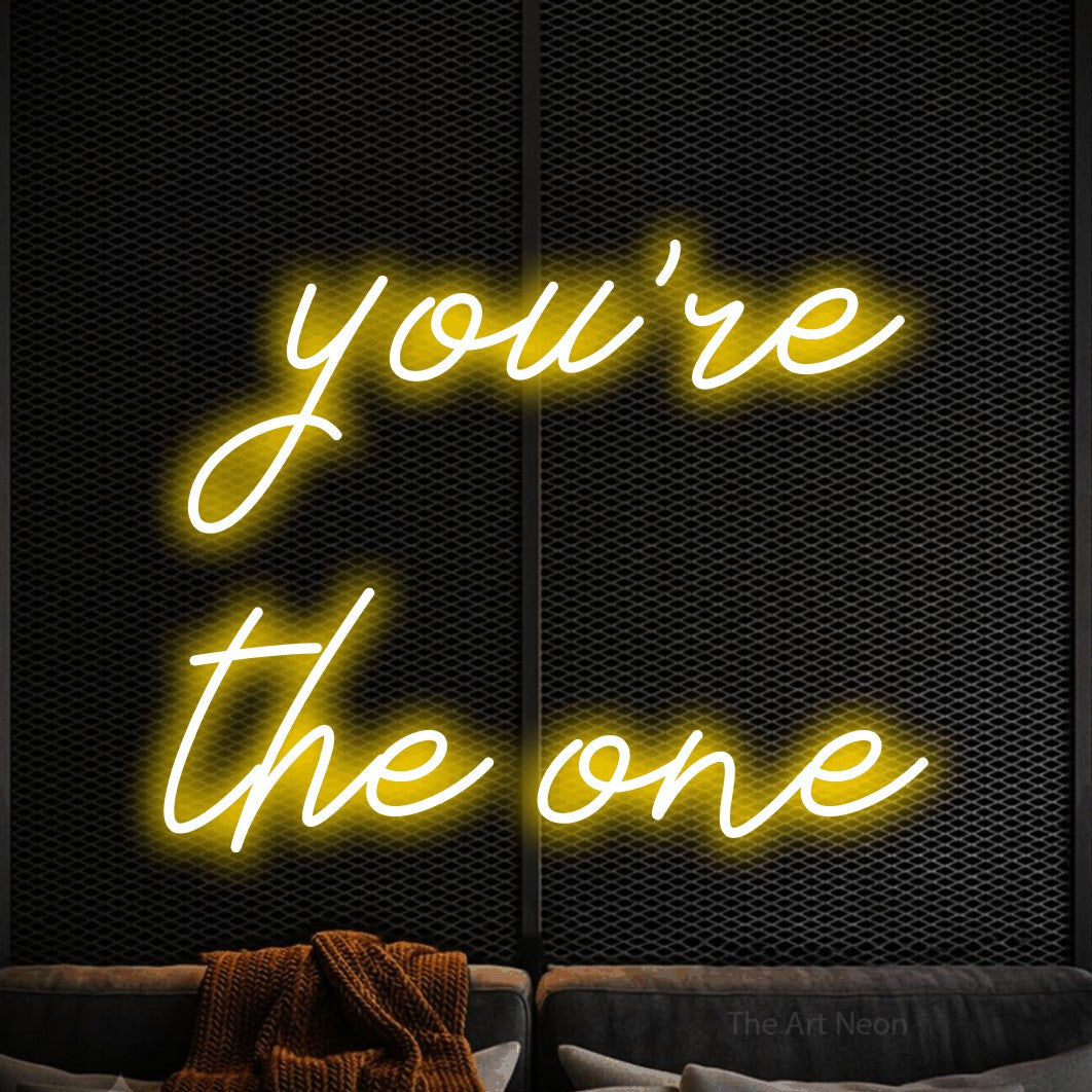 Yellow script-style LED neon sign reading "You're the One" against a black textured wall