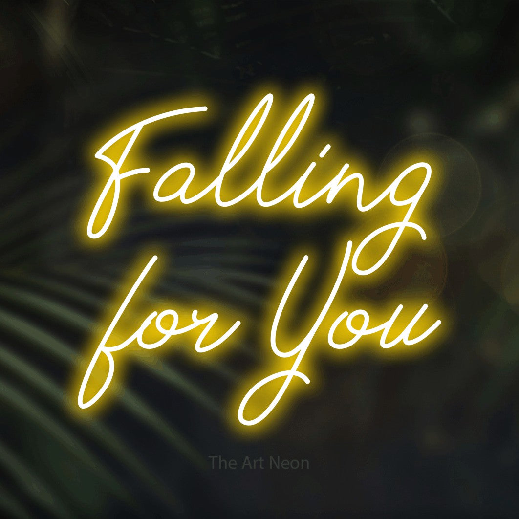 Yellow script-style LED neon sign reading "Falling for You" against dark blurred palm leaves