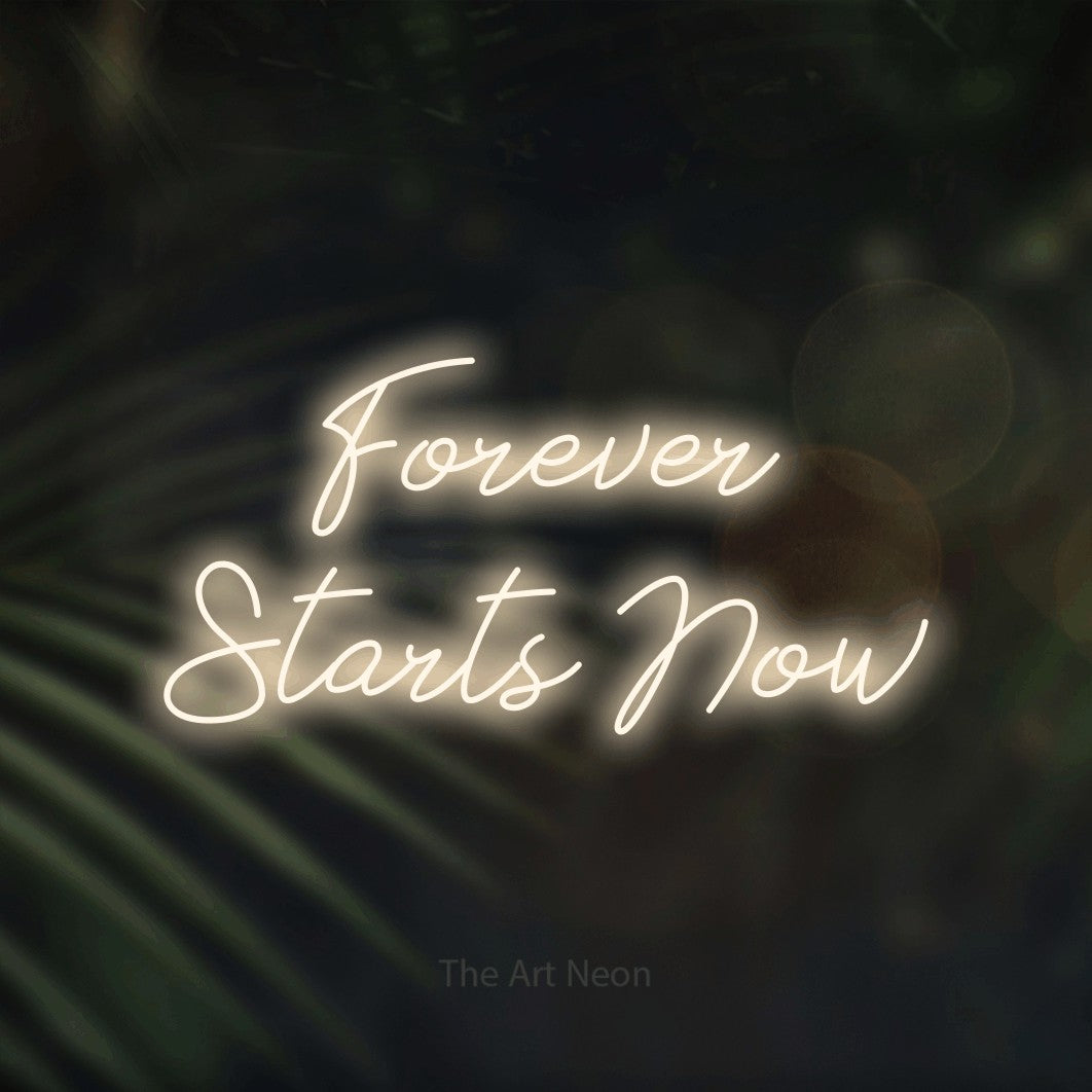 Enseigne néon à DEL à lumière blanche chaude, de style manuscrit, affichant « Forever Starts Now » sur des feuilles de palmier foncées et floues, pour décorer un mariage