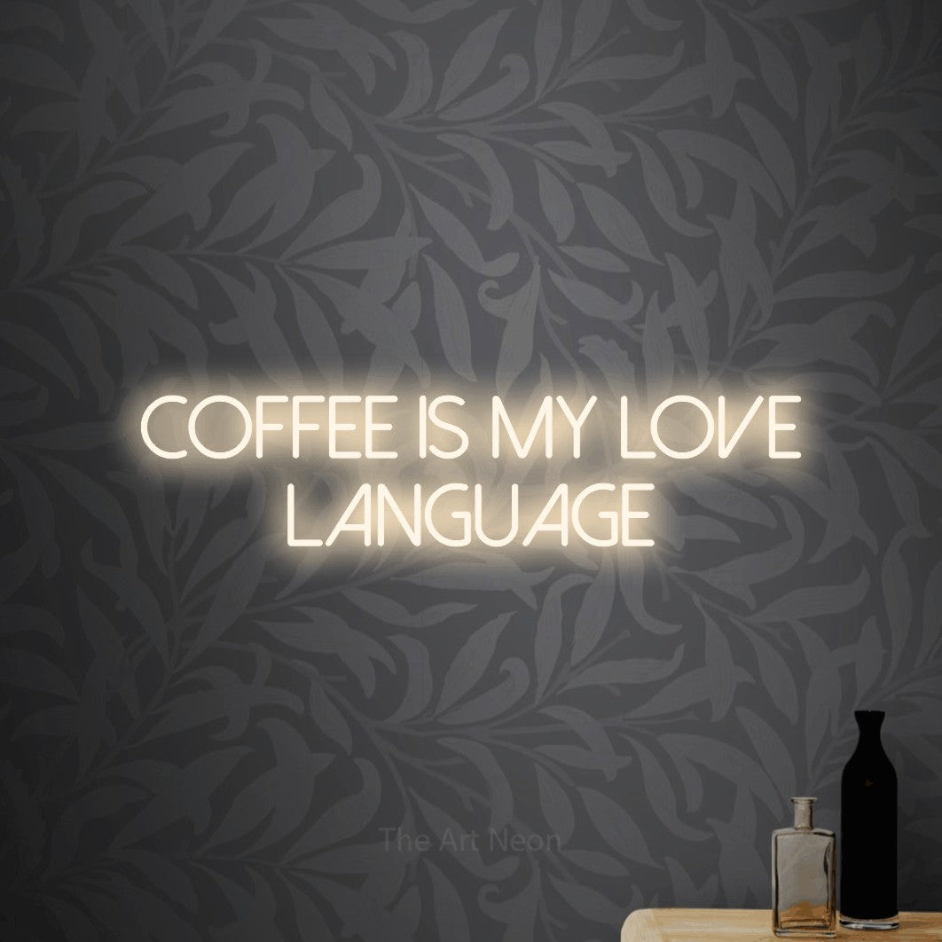 Warm white LED neon sign reading "Coffee is My Love Language" against light grey floral wallpaper for café décor