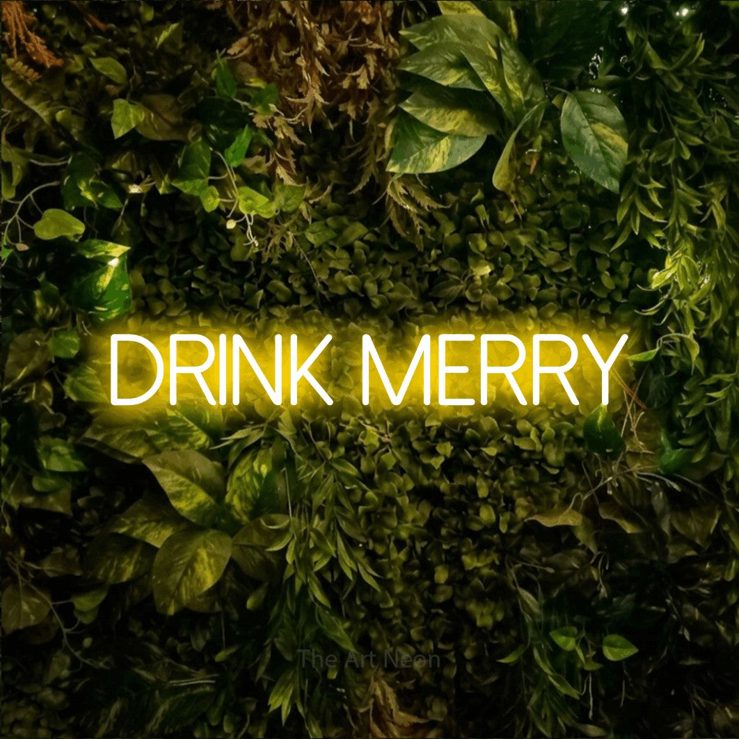 Yellow LED neon sign reading "Drink Merry" against a textured moss and foliage wall for bar décor