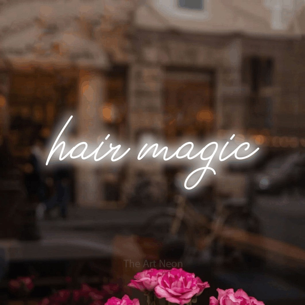 Cool white script-style LED neon sign reading "Hair Magic" in a softly blurred café interior for salon décor
