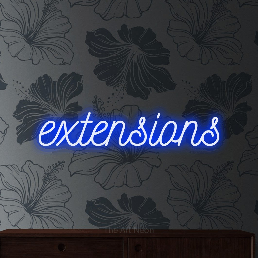 Blue script-style LED neon sign reading "Extensions" against grey floral wallpaper for salon décor