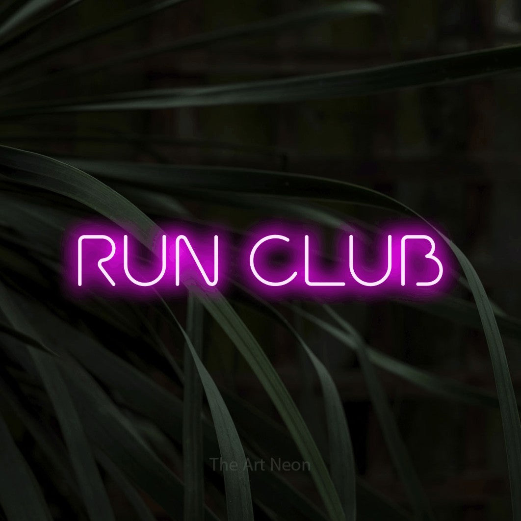 Pink LED neon sign reading "Run Club" against dark tropical leaves for gym décor