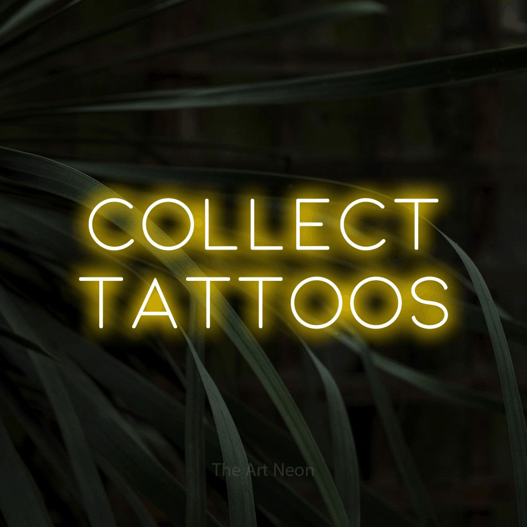 Yellow LED neon sign reading "Collect Tattoos" against dark tropical leaves for tattoo studio décor