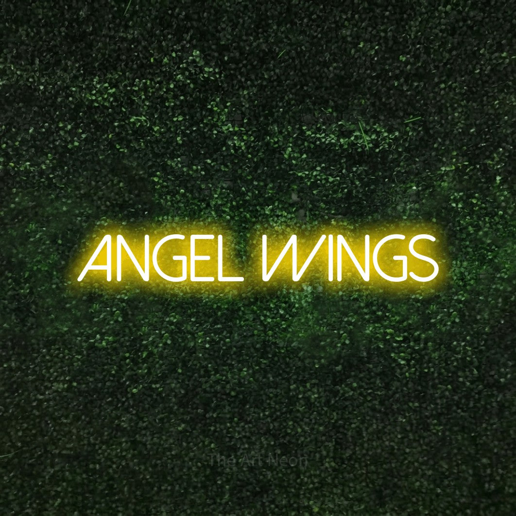 Yellow LED neon sign reading "Angel Wings" against a textured green moss wall for tattoo studio décor