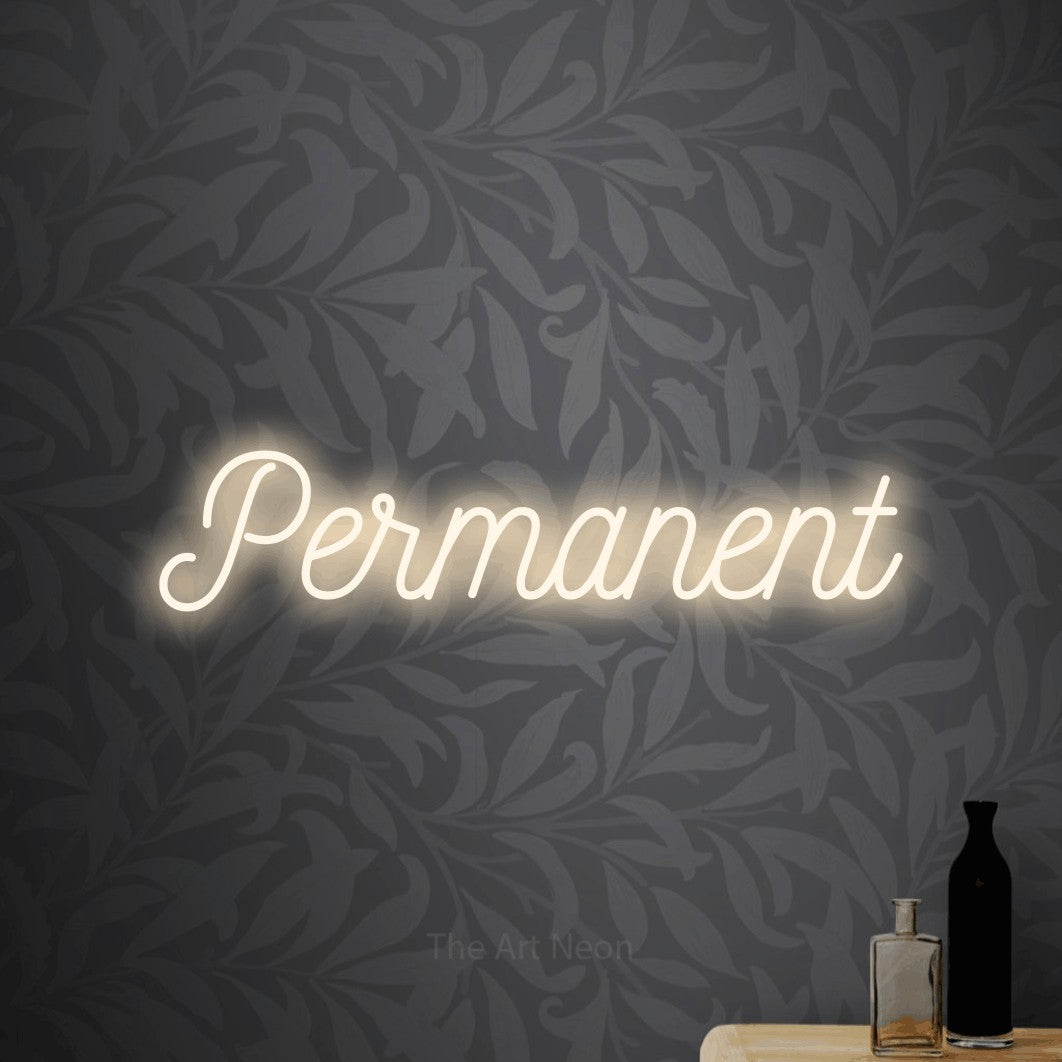 Warm white script-style LED neon sign reading "Permanent" against light grey floral wallpaper for tattoo studio décor