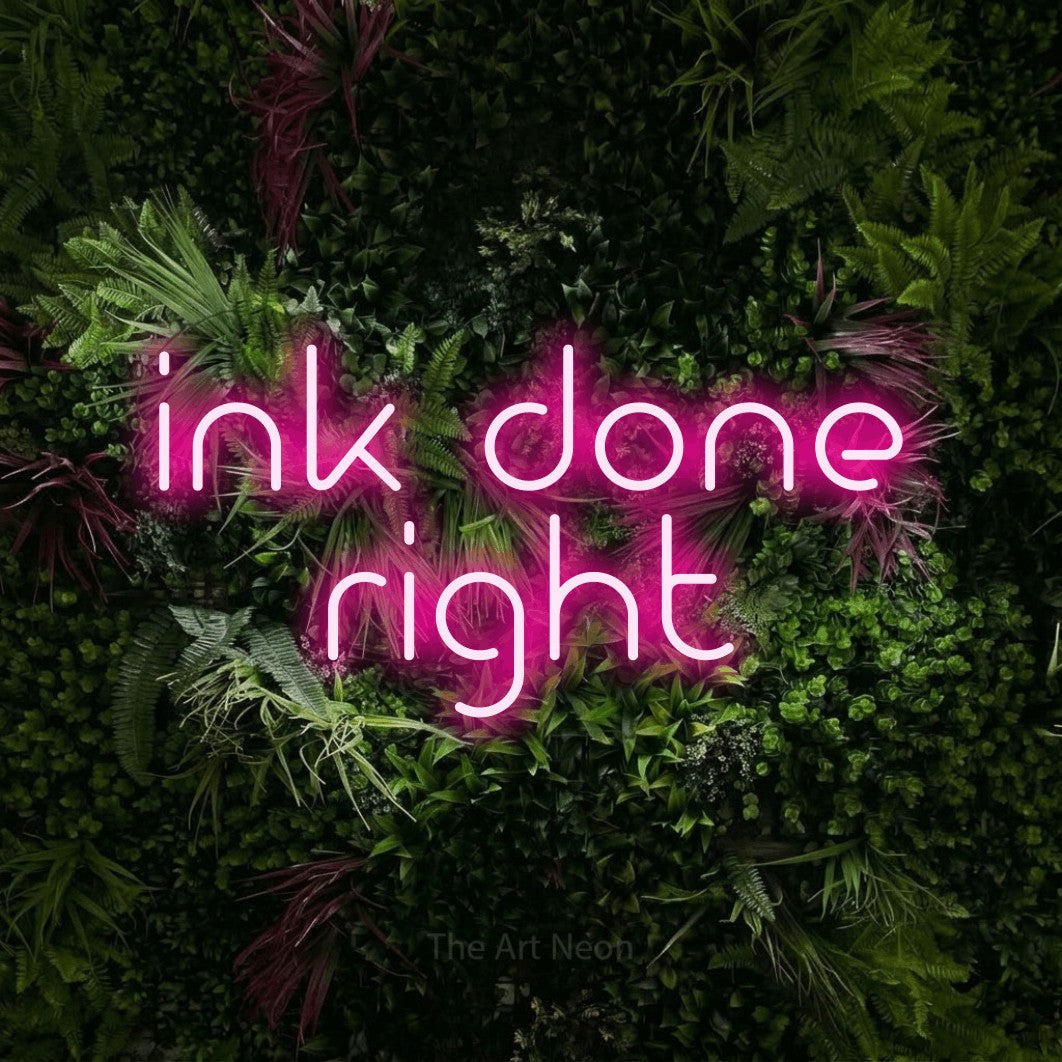Hot pink LED neon sign reading "Ink Done Right" against a lush garden wall with pink flowers for tattoo studio décor
