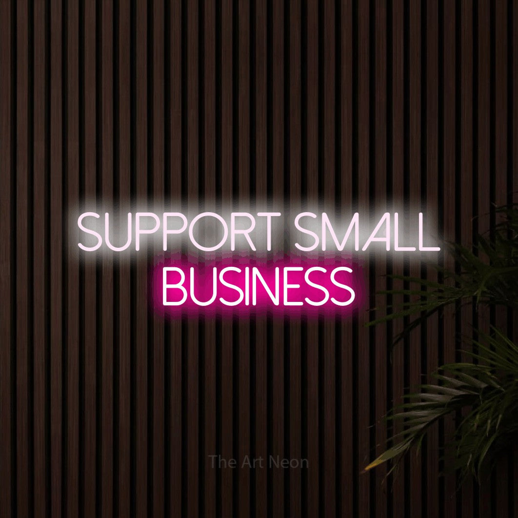 Hot pink and cool white LED neon sign reading "Support Small Business" against dark wooden slats