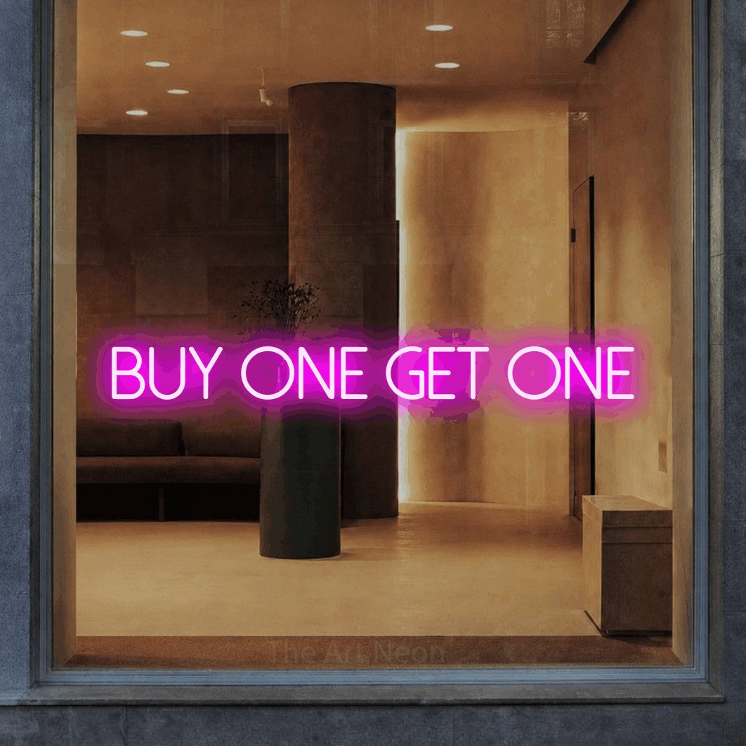 Pink LED neon sign reading "Buy One Get One" in a warm modern interior