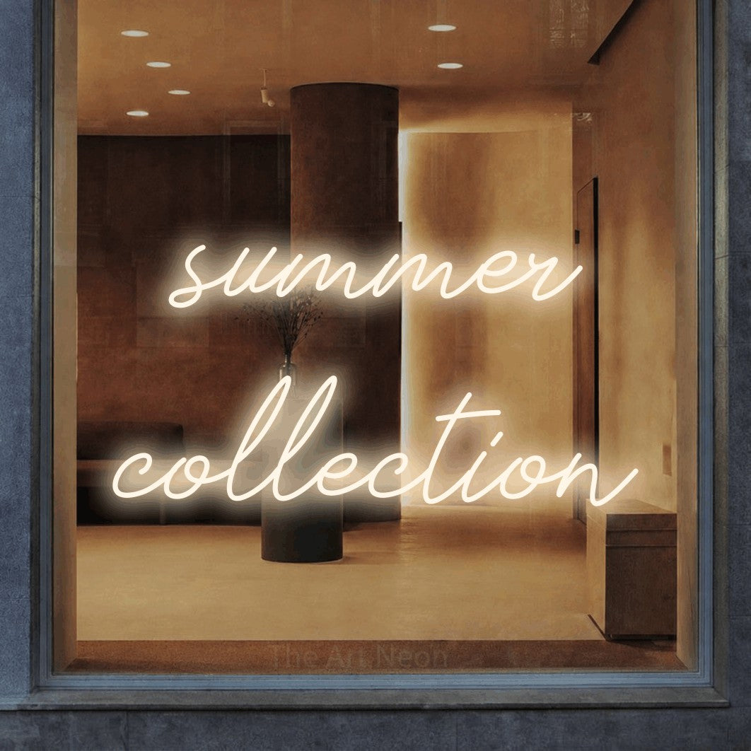 Warm white script-style LED neon sign reading "Summer Collection" in a warm modern interior