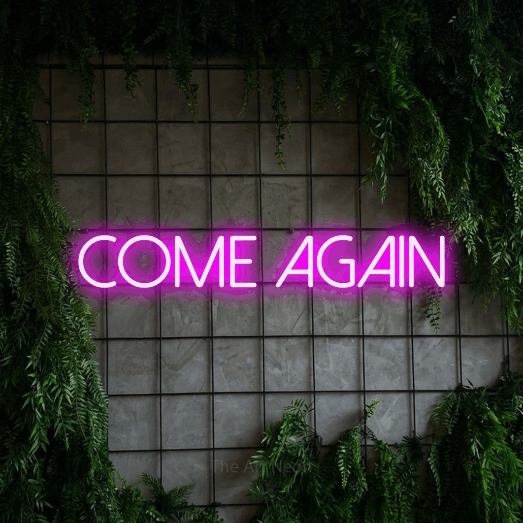 Pink LED neon sign reading "Come Again" against a green grid wall with foliage