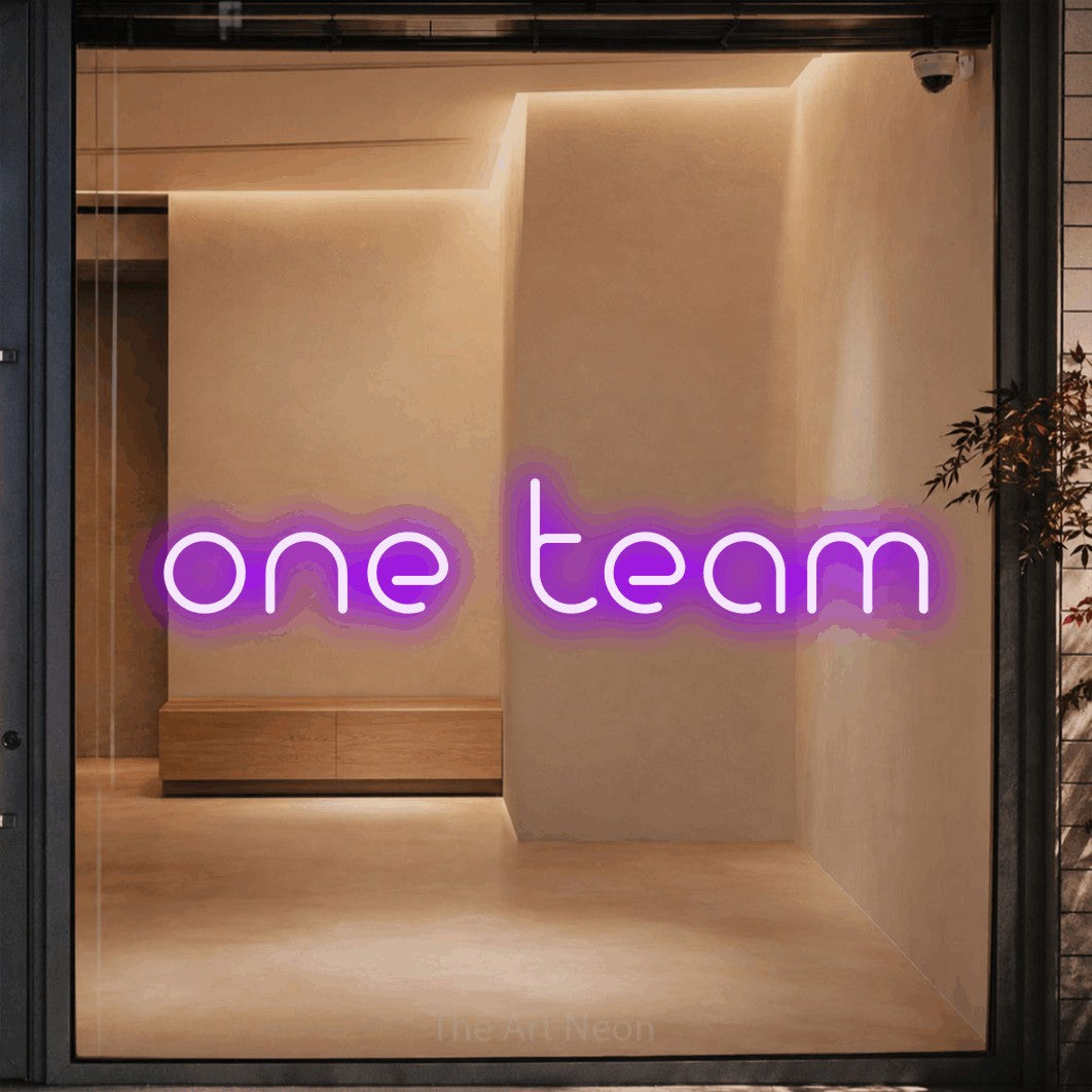 Purple LED neon sign reading "One Team" against a warm beige alcove wall for office décor