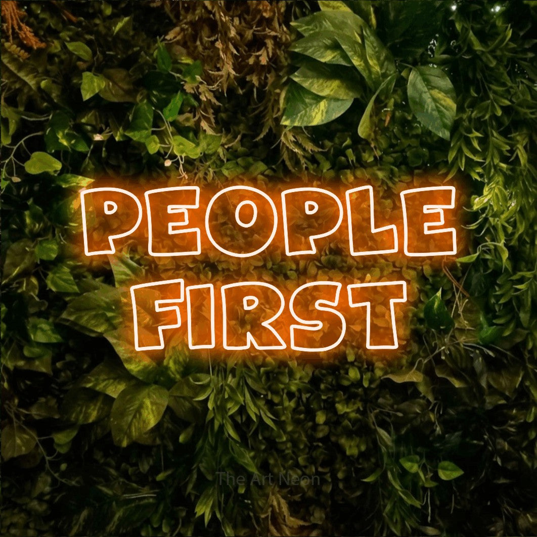 Orange outline-style LED neon sign reading "People First" against a textured moss and foliage wall for office décor