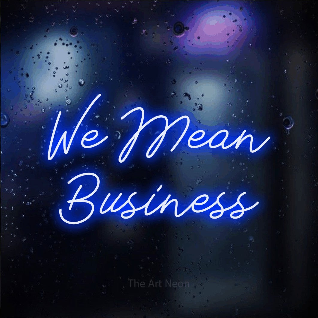 Blue script-style LED neon sign reading "We Mean Business" against a dark blue bokeh background for office décor