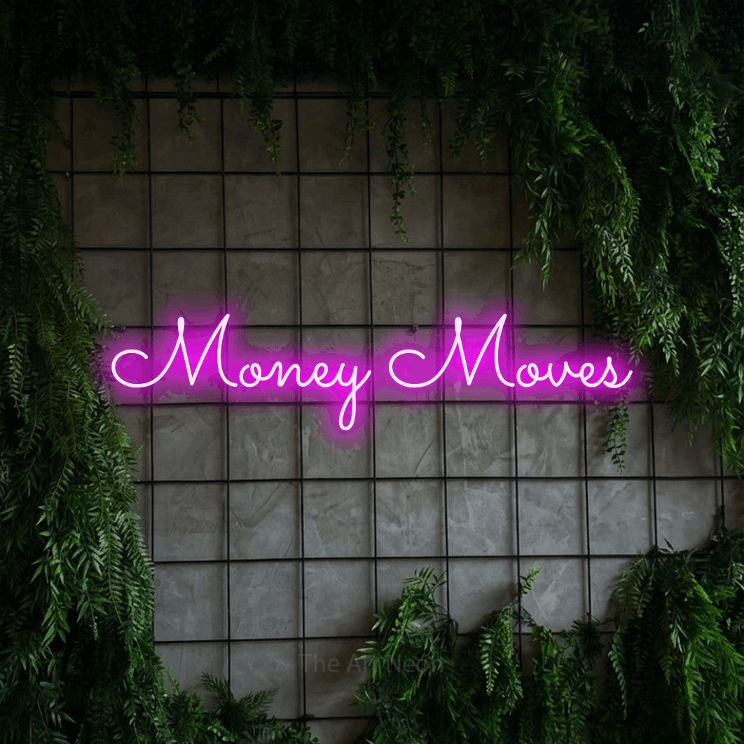 Pink LED neon sign reading "Money Moves" against a green grid wall with foliage for office décor