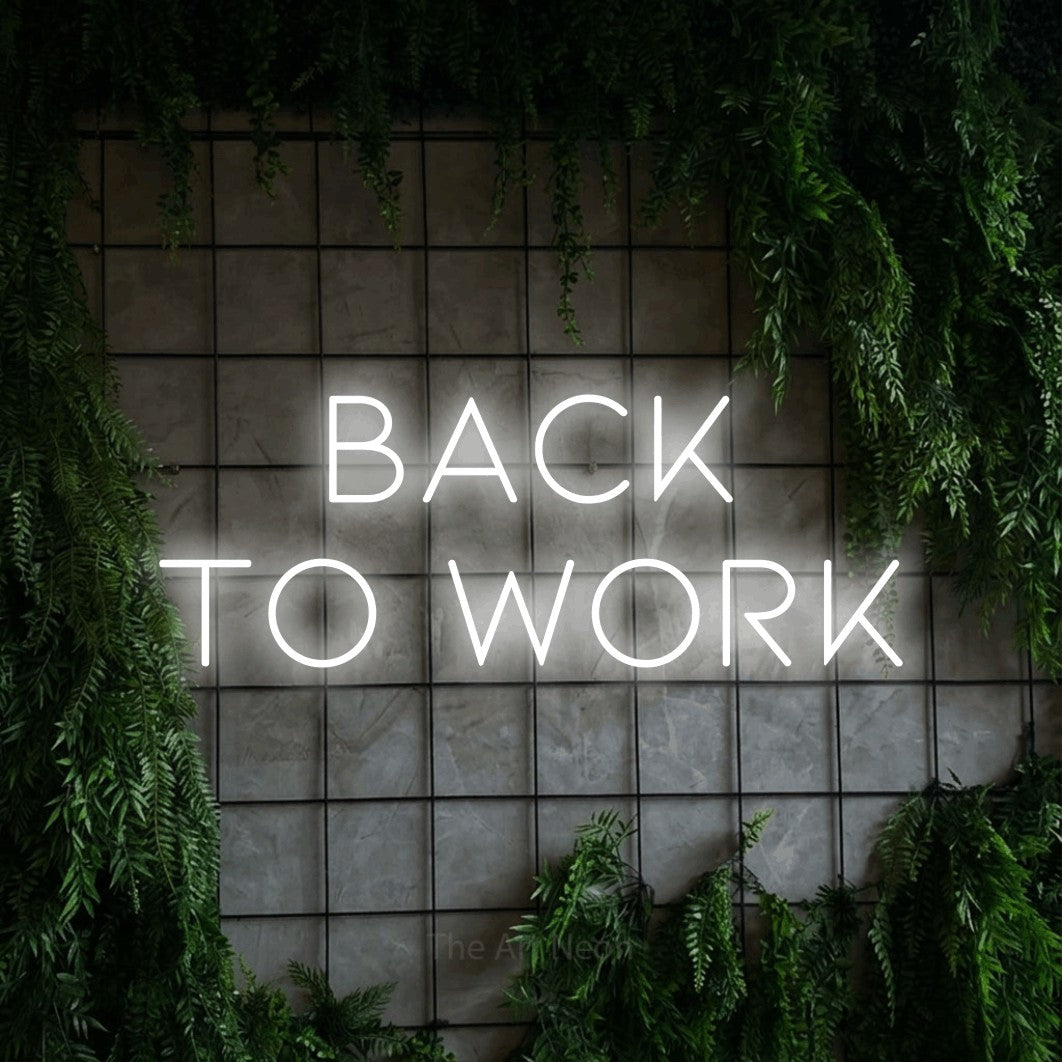 Cool white LED neon sign reading "Back to Work" against a green grid wall with foliage for office décor