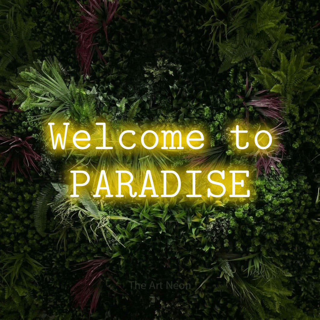 Yellow LED neon sign reading "Welcome to Paradise" against a lush garden wall with pink flowers for hotel décor