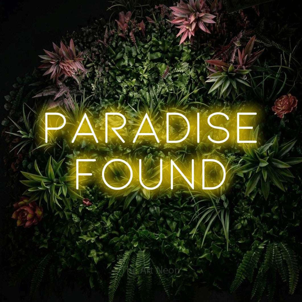 Yellow LED neon sign reading "Paradise Found" against a flowering garden wall for hotel décor