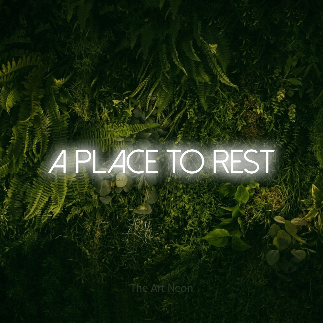 Cool white LED neon sign reading "A Place to Rest" against a moss-covered green wall for hotel décor
