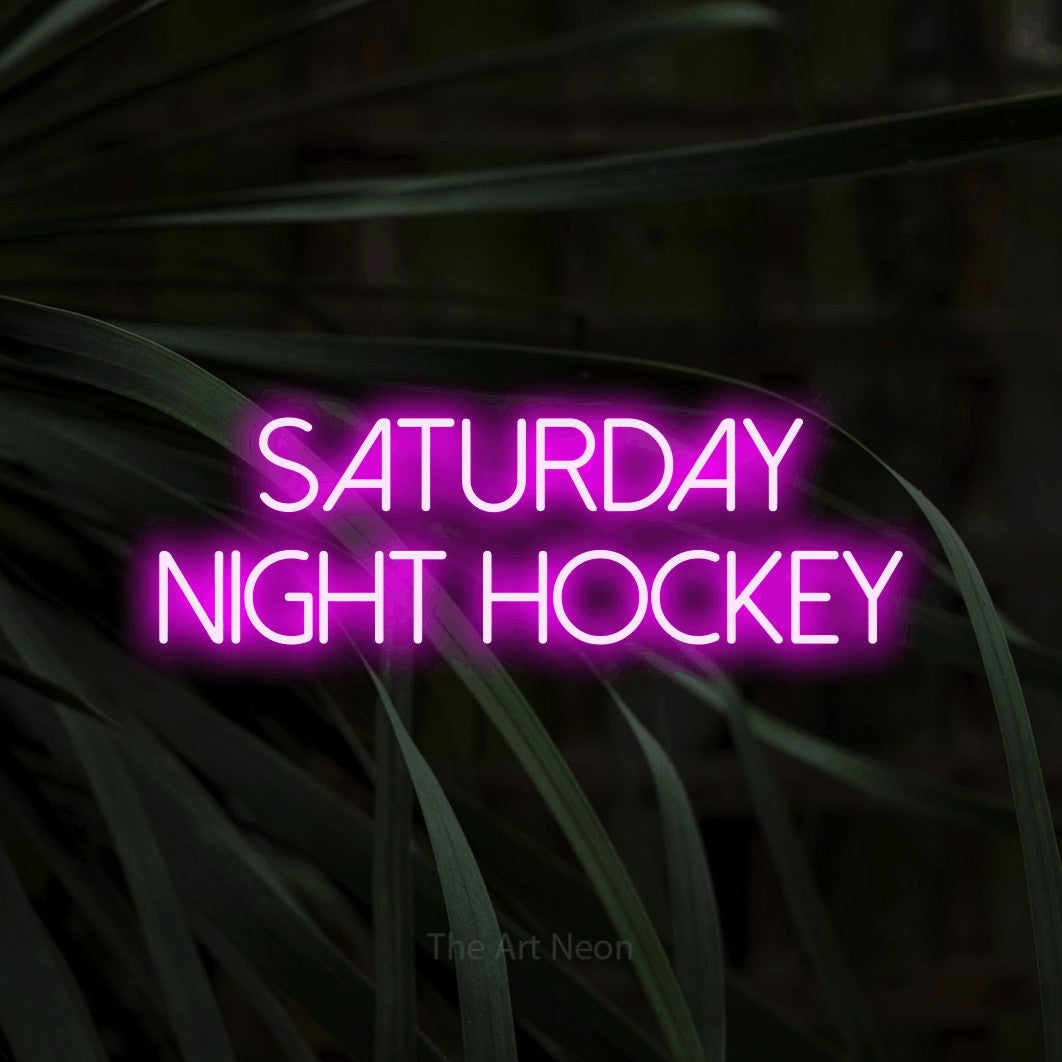 Pink LED neon sign reading "Saturday Night Hockey" against dark tropical leaves