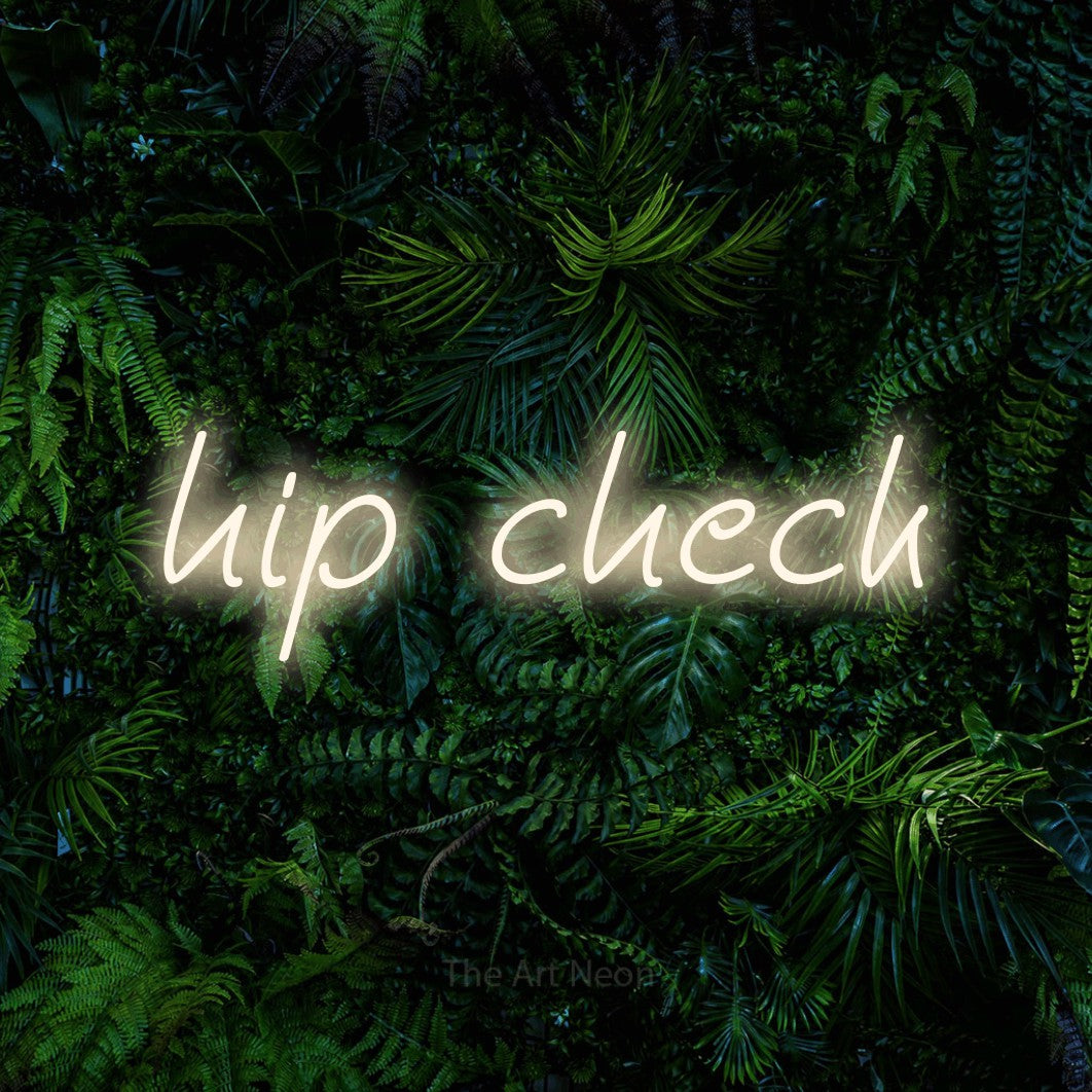 Warm white LED neon sign reading "Hip Check" against a dense tropical foliage wall