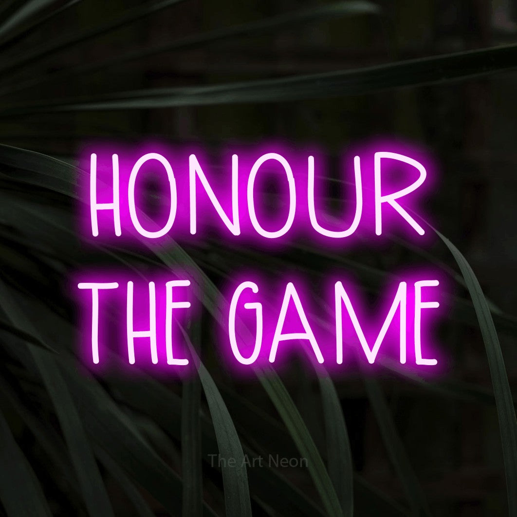 Enseigne néon à DEL à lumière rose, affichant « Honour the Game » sur des feuilles tropicales foncées