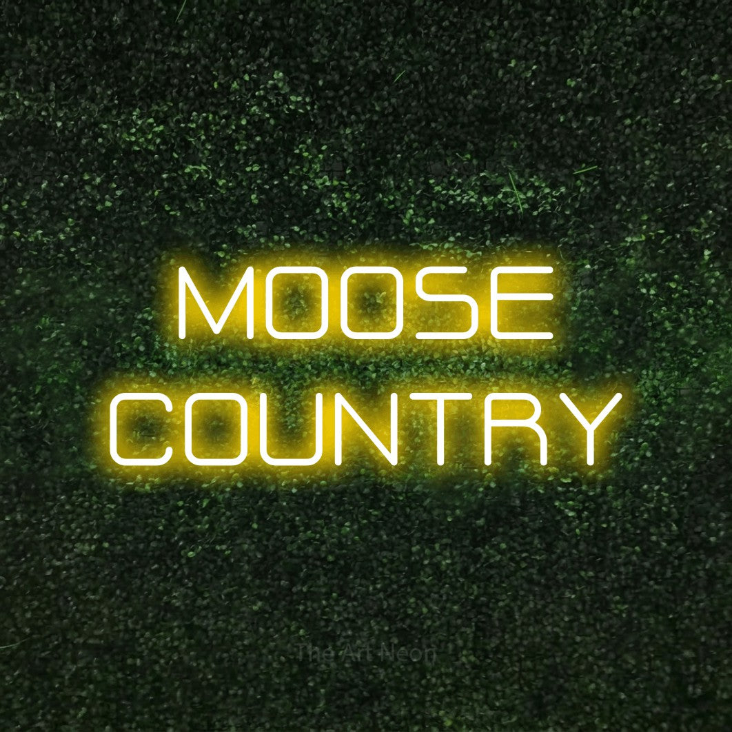 Yellow LED neon sign reading "Moose Country" against a textured green moss wall