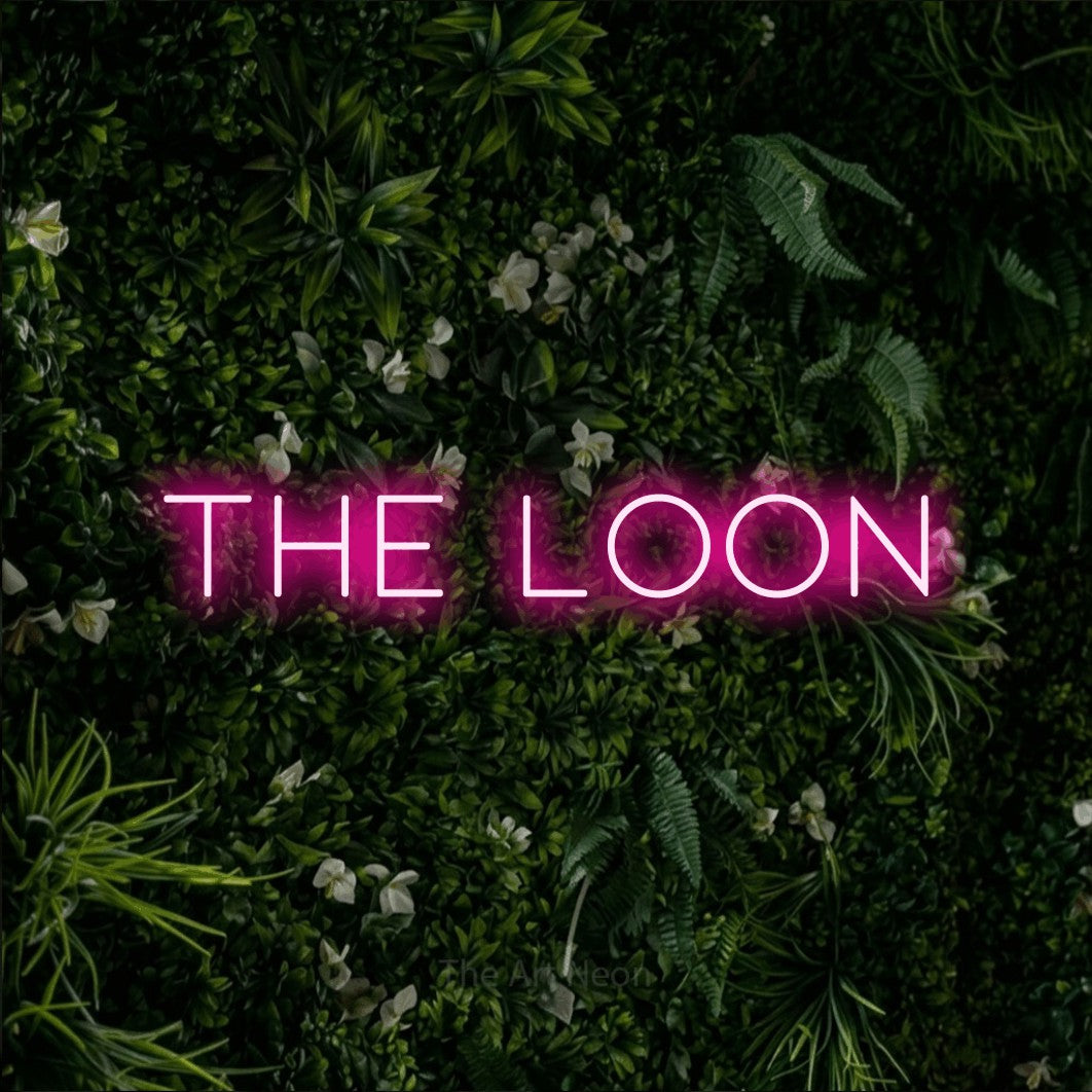 Hot pink LED neon sign reading "The Loon" against a leafy green wall