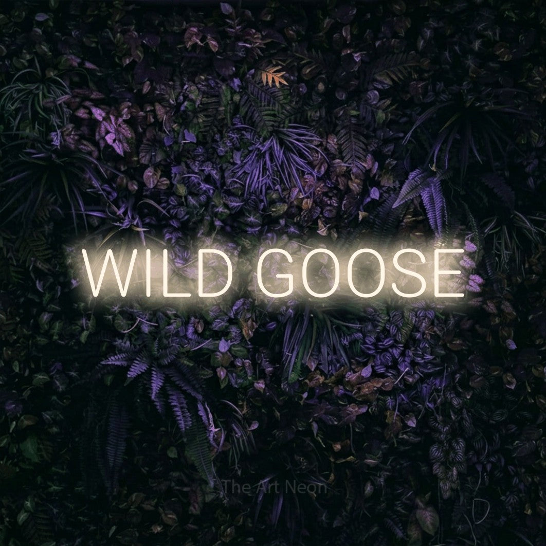 Warm white LED neon sign reading "Wild Goose" against a purple floral wall