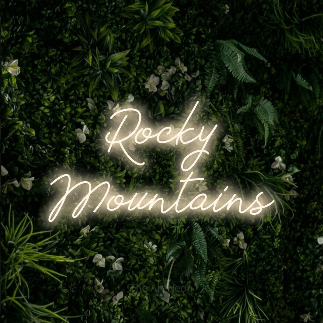 Enseigne néon à DEL à lumière blanche chaude, de style manuscrit, affichant « Rocky Mountains » sur un mur de feuillage vert