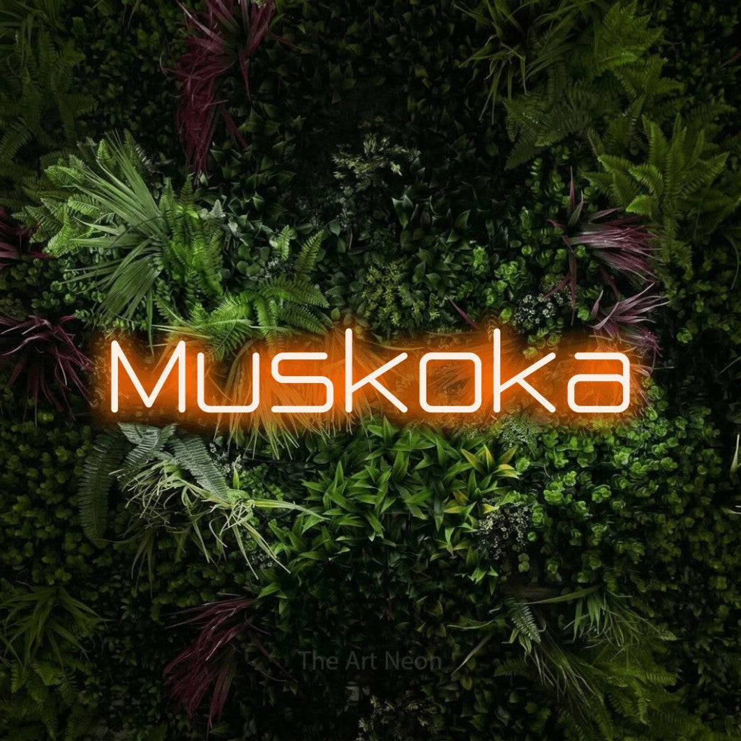 Orange LED neon sign reading "Muskoka" against a lush garden wall with pink flowers