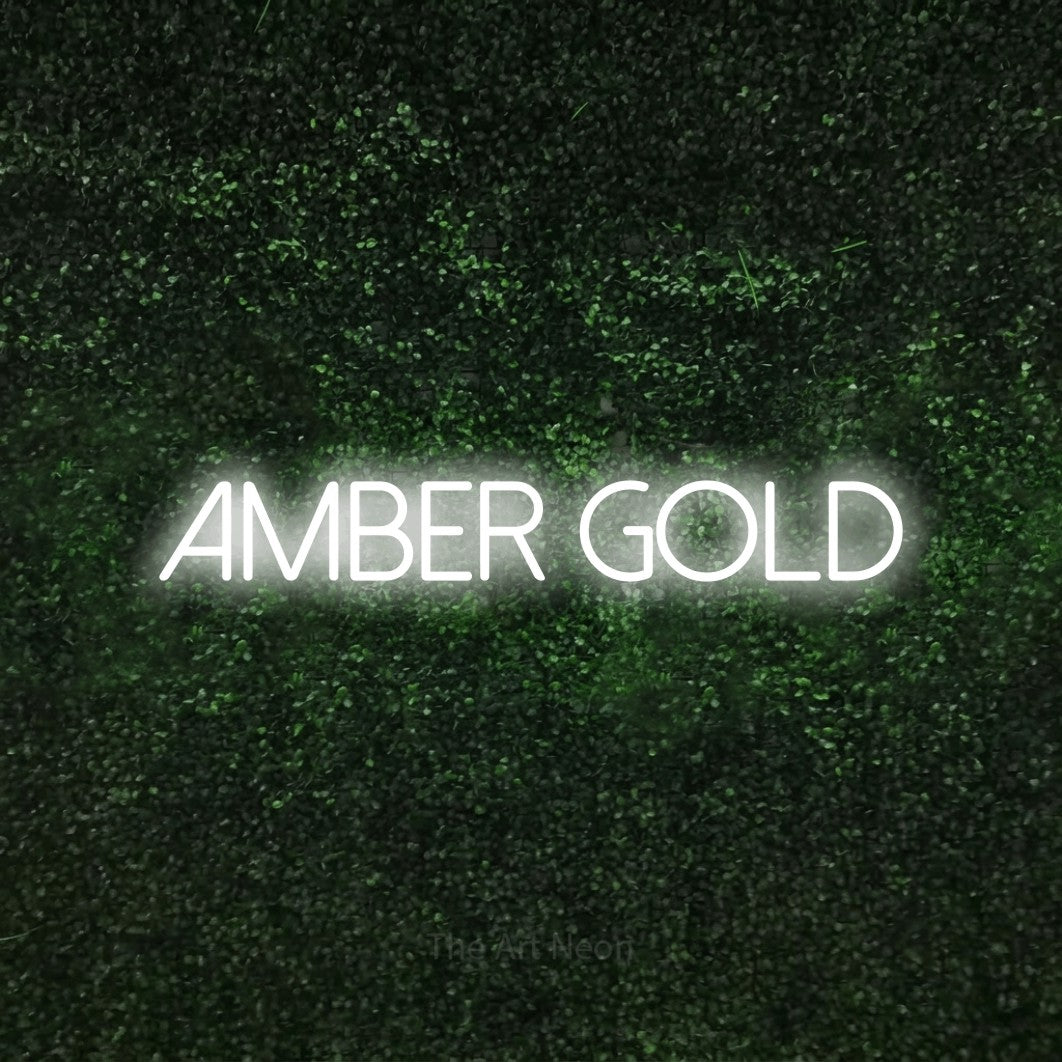 Enseigne néon à DEL à lumière blanche froide, affichant « Amber Gold » sur un mur texturé de mousse verte