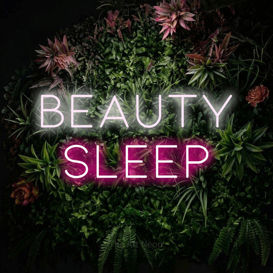 Hot pink and cool white LED neon sign reading "Beauty Sleep" against a flowering garden wall for bedroom décor